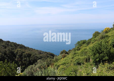 Bleu clair de la mer et du ciel avec un excès de bateau à travers le paysage vu à partir d'un sentier de randonnée entre les villages de Cinque Terre, italie Banque D'Images