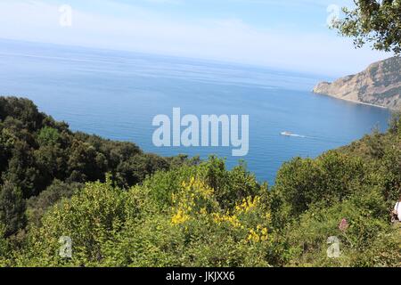 Bleu clair de la mer et du ciel avec un excès de bateau à travers le paysage vu à partir d'un sentier de randonnée entre les villages de Cinque Terre, italie Banque D'Images