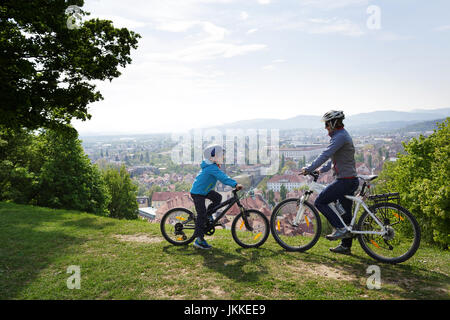 Mère et fils à vélo au château avec vue panoramique sur la vieille ville de Ljubljana, Slovénie. Banque D'Images