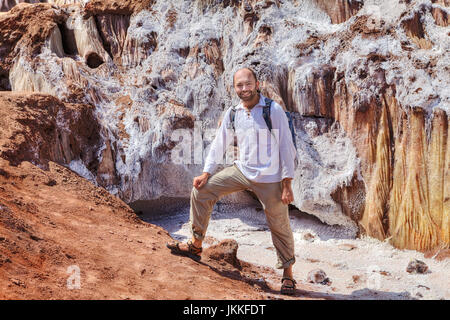Smiling tourist posant pour un photographe sur la toile de fond les glaciers de sel de roche, au cours d'une randonnée d'attractions naturelles de l'île d'Ormuz, Banque D'Images