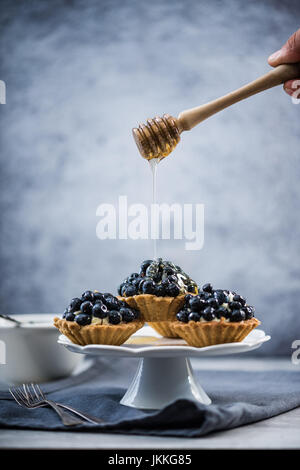 Tarte aux bleuets trempette miel sur mini tarte, copy space background Banque D'Images