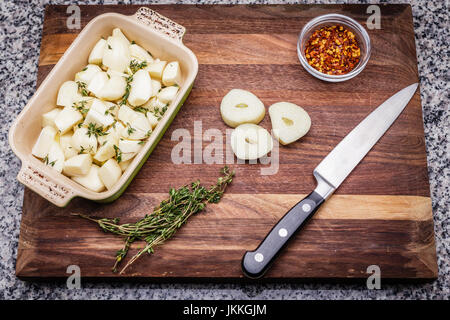 Ingrédients pour la préparation de l'ail rôti au thym frais, comprend et piment rouge broyé. L'ail haché dans un plat de cuisson en céramique. Couteau et roasti Banque D'Images