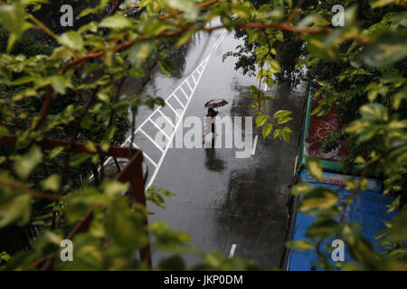 Dhaka, Bangladesh. 24 juillet, 2017. Une femme porte bangladais parapluie pour protéger de la pluie elle-même comme elle filtre la gratuites Street à Dhaka. Credit : Md. Mehedi Hasan/ZUMA/Alamy Fil Live News Banque D'Images