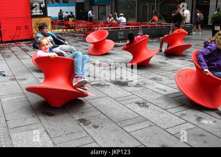 New York, États-Unis. 24 juillet, 2017. New York, NY, US. -- 24 juillet 2017-- Les jeunes et les jeunes de cœur les visiteurs de Times Square s'arrêta un moment de plaisir avec le midi Magis Chaise. filé Le filé debout est une fascinante chaises chaise qui ressemble plus à un navire sculpturale d'un siège. Mais lorsqu'il se penche sur le côté, elle forme un siège confortable et fonctionnel qui vous permet d'latéralement ou tourner autour. Credit : Ronald G. Lopez /DigiPixsAgain.us/Alamy Live News Banque D'Images
