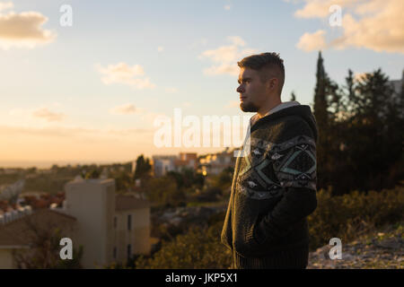 Jeune homme solitaire se dresse sur la montagne et regarde dans la distance Banque D'Images