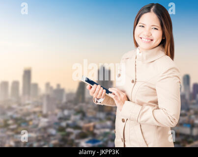 Asian woman wearing pelage brun et holding tablet Banque D'Images