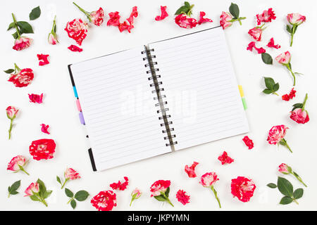 Composition de fleurs. Cadre fait de fleurs rose. Ordinateur portable ou de journal intime ouvert au milieu. Mise à plat, vue du dessus Banque D'Images