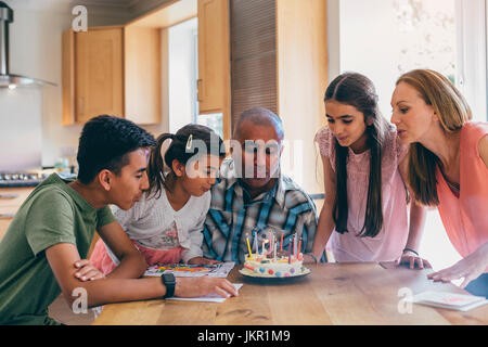 Famille heureuse fête des pères anniversaire. Ils sont tous l'aider à souffler les bougies sur son gâteau. Banque D'Images