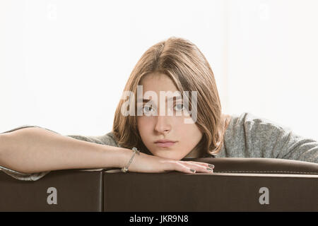 Portrait of teenage girl sitting on sofa against white background Banque D'Images