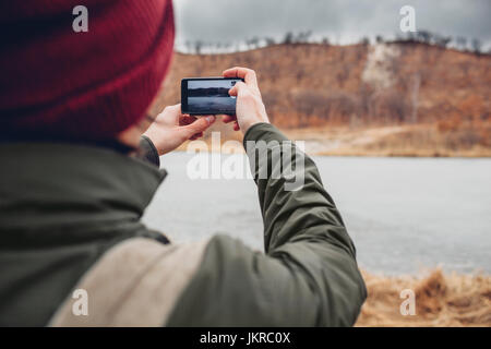 Vue arrière de l'homme photographie lac par smart phone, Blagovechtchensk, Amur, Russie Banque D'Images