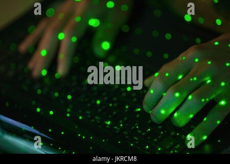 Close-up of green lights sur les mains coupées à l'aide du clavier d'ordinateur portable Banque D'Images