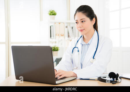 Le célèbre médecin femme asiatique travaillant avec son ordinateur au bureau et en visite en ligne patient soins avec application informatique et la saisie sur un Banque D'Images