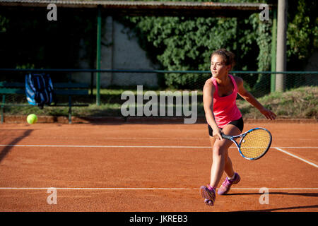 Jeune fille jouant au tennis sur terre battue rouge Banque D'Images