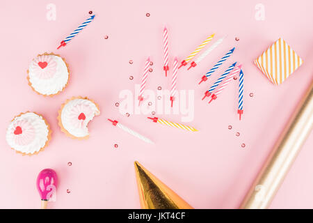 Vue de dessus de la petite boîte cadeau, bougies colorées et de délicieux petits gâteaux sur rose, anniversaire concept Banque D'Images