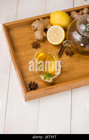 Tasse de thé au gingembre avec du citron et du miel sur fond de bois blanc. Banque D'Images