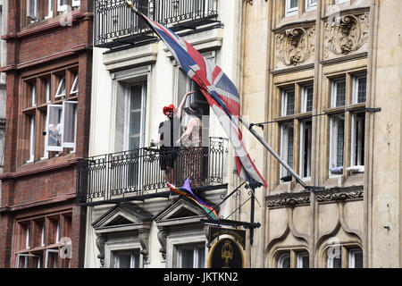 Les gens sur le balcon au-dessus du pub 'The Old Shades' à Whitehall, Londres, Royaume-Uni. Drapeaux Union Jack sur le bâtiment. Banque D'Images