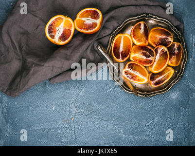 Bloody Red oranges siciliennes coupées en quartiers dans vintage plaque métallique sur fond texturé en béton Banque D'Images