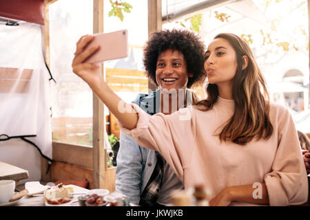 Jeune femme en tenant avec selfies homme africain dans la cafétéria. Young couple looking at smart phone dans le café. Banque D'Images