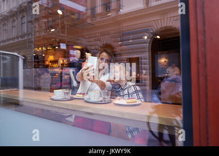 Jeune mère et fille passer du temps dans un café et faire des photos Banque D'Images