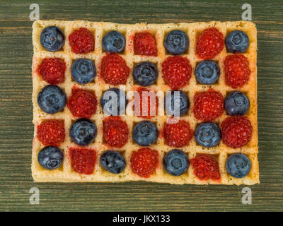 Les framboises et les bleuets sur une gaufre grillée sur un fond de bois vert Banque D'Images