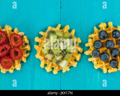 Gaufres beurre belge avec des bleuets et framboises kiwis against a blue background Banque D'Images