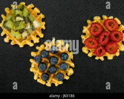 Gaufres beurre belge avec des Bleuets Framboises et kiwis sur un fond noir Banque D'Images