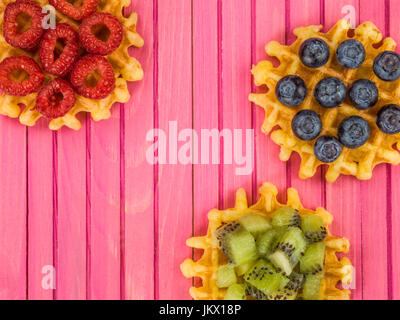 Gaufres beurre belge avec des bleuets et framboises kiwis contre un fond de bois de rose Banque D'Images