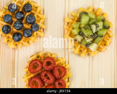 Gaufres beurre belge avec des bleuets et framboises kiwis contre un fond de bois en pin Banque D'Images