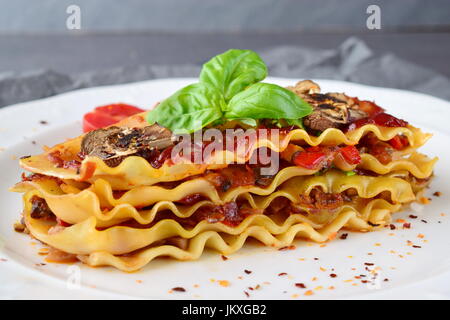 Lasagnes végétariennes avec champignons, oignons, olives et sauce tomate sur une plaque blanche. Concept de saine alimentation. Mode de vie méditerranéen. Banque D'Images