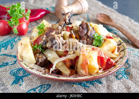 Ragoût traditionnel avec les côtelettes d'agneau et de légumes : oignons, choux, pomme de terre, tomate, paprika dans un bol sur un tissu de fond. Concept de saine alimentation. Banque D'Images