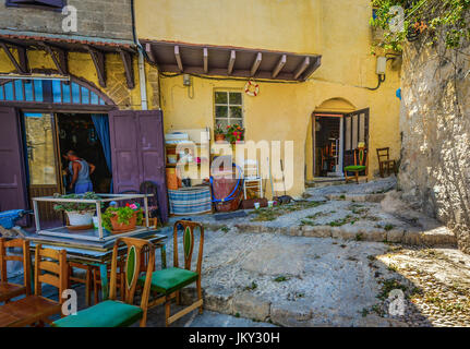 À l'écart pour les affaires d'ouverture café sur l'île Méditerranéenne de Rhodes, Grèce. Un chat chasse un pigeon et les tiges à l'extérieur de la porte. Banque D'Images