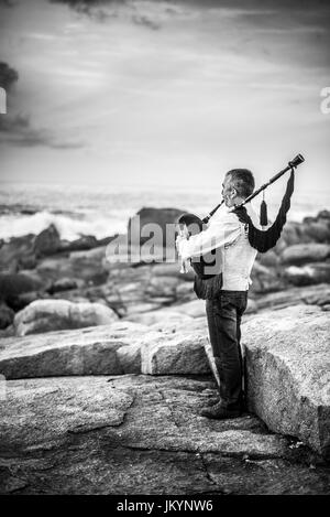 L'homme jouant sur la cornemuse sur la côte de l'océan dans l'Espagne, l'Europe, Muxia, Camino de Santiago. Banque D'Images