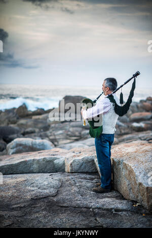 L'homme jouant sur la cornemuse sur la côte de l'océan dans l'Espagne, l'Europe, Muxia, Camino de Santiago. Banque D'Images