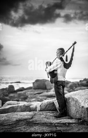 L'homme jouant sur la cornemuse sur la côte de l'océan dans l'Espagne, l'Europe, Muxia, Camino de Santiago. Banque D'Images