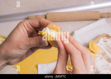 Vue rapprochée de woman's hands la préparation pour la cuisine vareniki, boulettes, pierogi avec du fromage cottage ou une pâte alimentaire traditionnelle ukrainienne. Pi Matériel roulant Banque D'Images