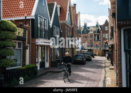 Volendam, Pays-Bas - 26 avril, 2017 : habitant du village de Volendam en vélo en face de la typique des maisons traditionnelles de la pêche néerlandais vill Banque D'Images