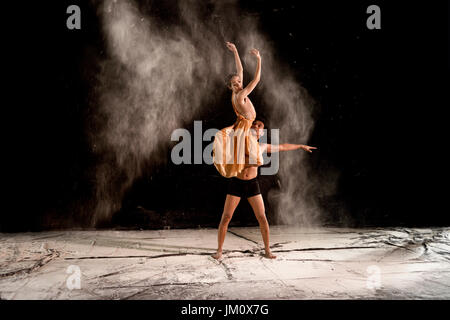 Jeune couple danse classique avec la poudre dans la scène sur fond noir Banque D'Images