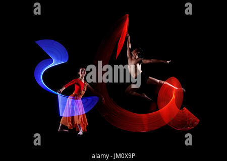 Beau couple danseur de ballet avec effet de lumières colorées sur fond noir Banque D'Images