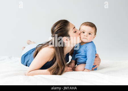 Portrait de Mère embrassant son enfant adorable tout en lying on bed Banque D'Images