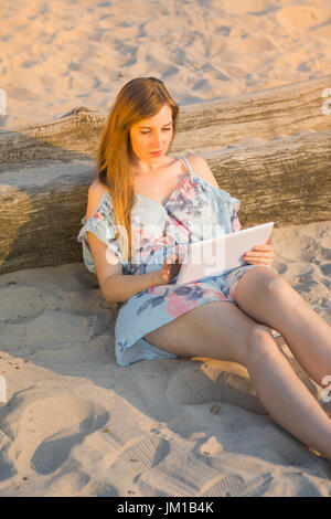 Belle jeune femme surf sur internet tablet at beach Banque D'Images