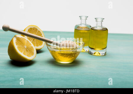 Vue rapprochée d'huile essentielle dans de petites bouteilles, le miel dans un bol et les tranches de citron sur la table en bois Banque D'Images