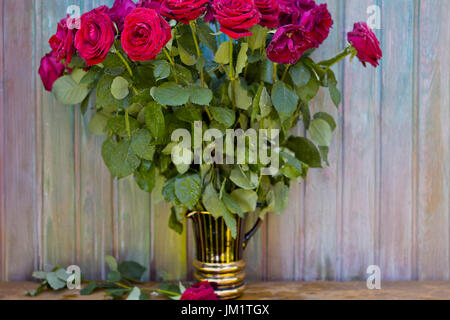 Bouquet de roses rouges dans un vase contre le mur en bois peint, selective focus photo plein air Banque D'Images