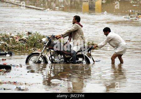 Sanaa, Yémen. Le 25 juillet, 2017. Un homme tente d'aider un motocycliste hors de l'inondation après les fortes pluies dans la région de Sanaa, capitale du Yémen, le 25 juillet 2017. Les autorités yéménites ont mis en garde les gens à prendre des précautions pour les torrents et éboulis en raison de fortes pluies ces derniers jours. Credit : Mohammed Mohammed/Xinhua/Alamy Live News Banque D'Images