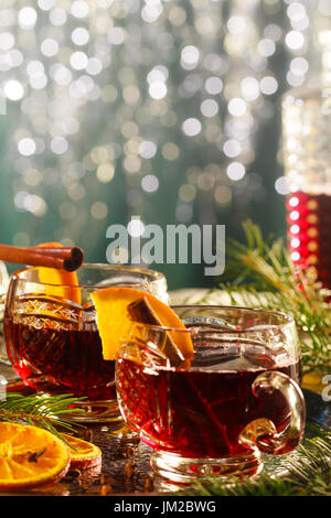 Vin chaud sur verres décoratifs avec des tranches d'orange, l'arrière-plan flou de Noël. Banque D'Images