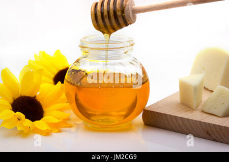 Pot de miel avec du fromage sur une planche à découper Banque D'Images