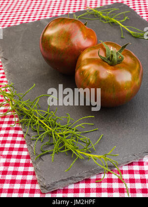 Les tomates et les herbes sur une ardoise Banque D'Images