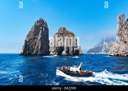Bateaux de croisière autour de la faraglioni dans la mer tyrrhénienne, le long de la côte de l'île de Capri, Italie. Banque D'Images