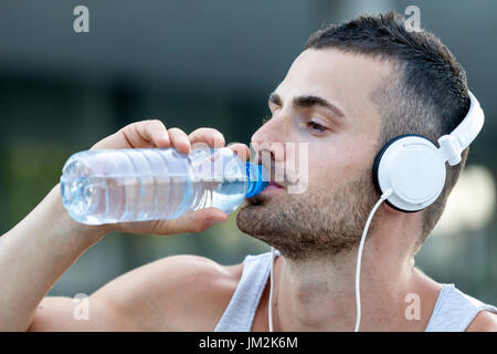 Portrait de jeune homme un peu d'eau potable à partir d'une bouteille après la formation. Banque D'Images