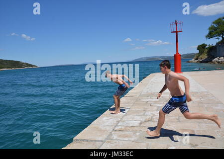 Cres, Croatie - le 18 juin 2017 - Garçons sautant dans l'océan près de Osor sur île de Cres Banque D'Images