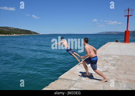 Cres, Croatie - le 18 juin 2017 - Garçons sautant dans l'océan près de Osor sur île de Cres Banque D'Images